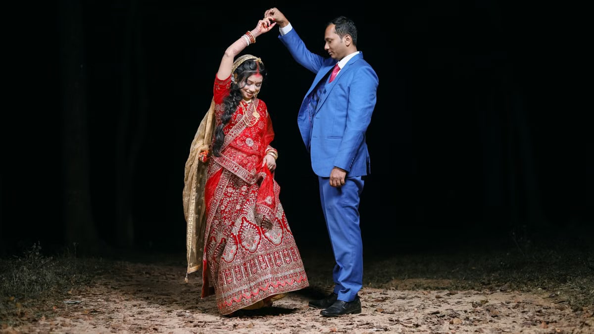 A couple gracefully dances during a nighttime Indian wedding, adorned in traditional attire.